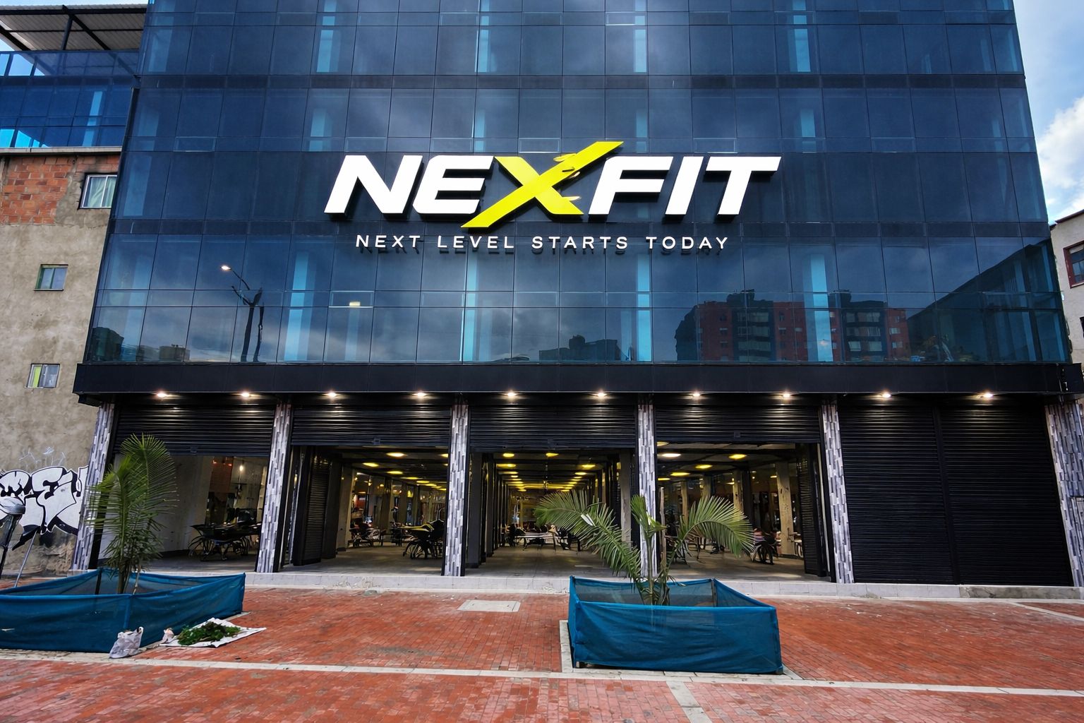 Edificio NEXFIT con logo dorado iluminado en la fachada